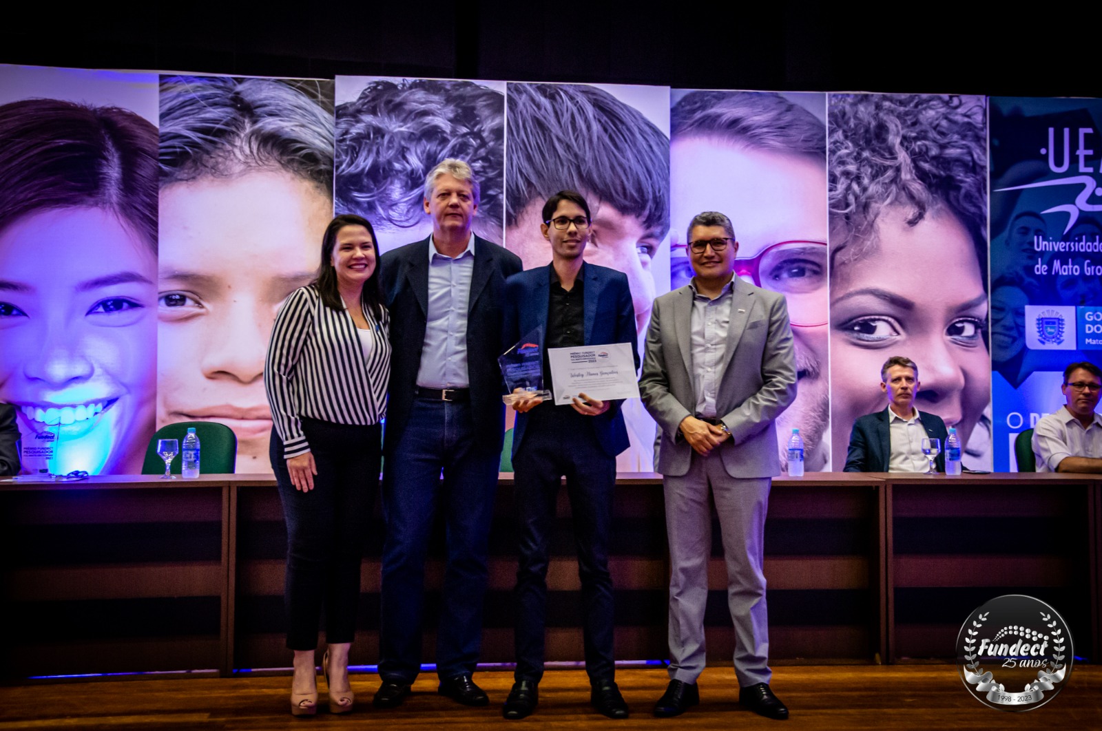 O pesquisador Wesley Nunes Gonçalves recebendo o Prêmio Pesquisador Sul-Mato-Grossense 2023 no Anfiteatro da UEMS. Ao seu lado esquerdo está o diretor-presidente da Fundect, Márcio de Araújo Pereira, e ao lado direito o Secretário da Semadesc, Jaime Verruck, e a vice-reitora da UFMS, Camila Itavo.